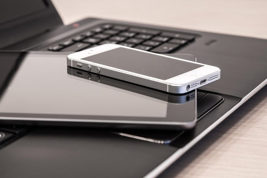 A phone and a tablet on top of a laptop